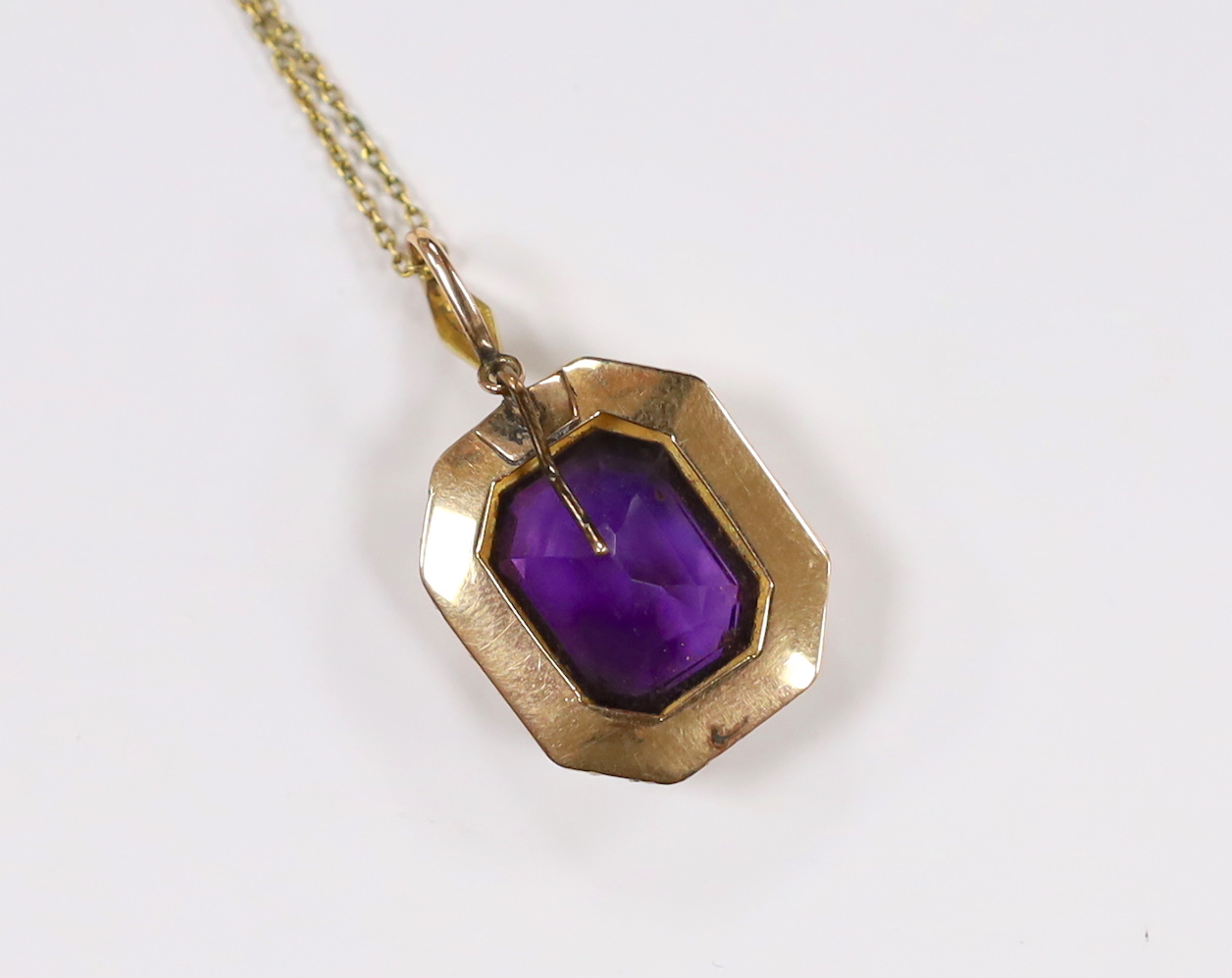 An Edwardian 15ct, amethyst and seed pearl cluster set pendant, overall 33mm, on a 9ct chain, 70cm, chain, 2.5 grams.